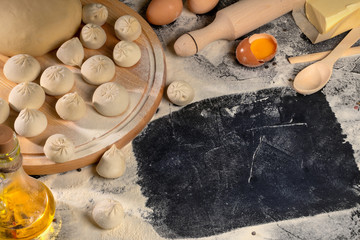 Hinkali homemade. Flour, eggs, dough on a black background. Top view. Free copy space