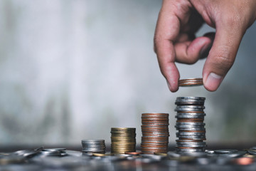 Save money concept with hand holding coin and stack growing business on abstract background