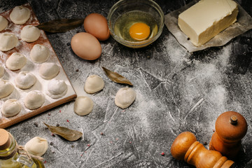 Homemade pelmeni, ravioli, dumplings with meat. Flour, eggs, fresh dough on a black background. Top view