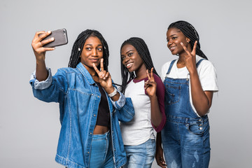 Portrait of pretty charming african girls shooting selfie on front camera using smart phone gesturing v-sign isolated on white background. Rest relax leisure concept
