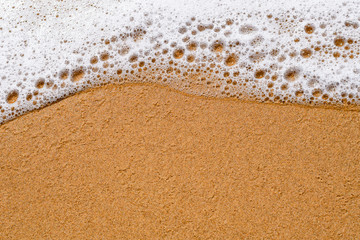 Sea wave cools down on the sandy beach, background