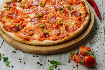 Pizza Pepperoni with mozzarella, salami, pepper and olives on the white wooden background