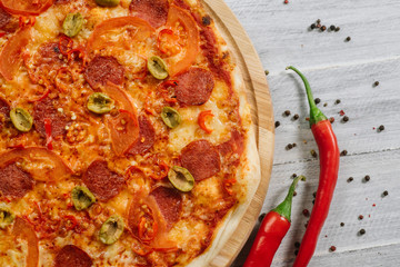 Pizza Pepperoni with mozzarella, salami, pepper and olives on the white wooden background