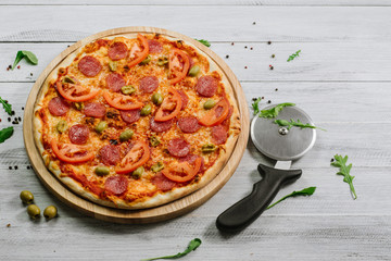 Delicious pizza Neapolitana with tomato sauce, mozzarella and ham on the white wooden background