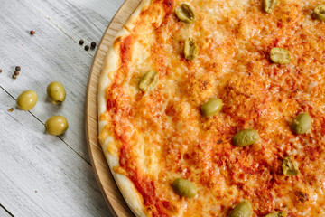 Tasty fresh pizza Margarita with mozzarella and olives on the white wooden background