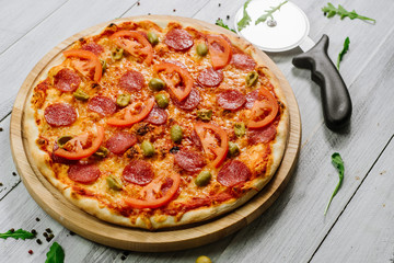 Delicious pizza Neapolitana with tomato sauce, mozzarella and ham on the white wooden background