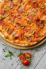 Tasty pizza Chachatore with mozzarella, salami and olives on the white wooden background