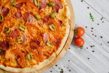Tasty pizza Chachatore with mozzarella, salami and olives on the white wooden background