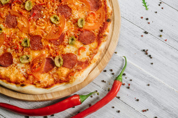 Pizza Pepperoni with mozzarella, salami, pepper and olives on the white wooden background