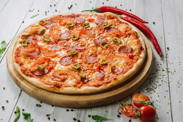 Pizza Pepperoni with mozzarella, salami, pepper and olives on the white wooden background