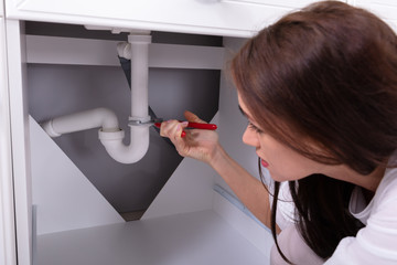 Woman Repairing Sink With Adjustable Wrench