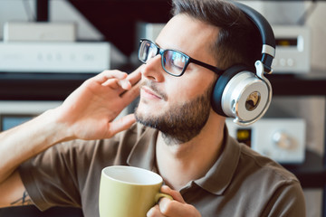 Mann trinkt Kaffee und hört dabei Musik