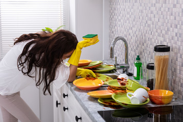 Tired Woman Leaning Near Sink With Dirty Utensils