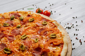 Tasty pizza Chachatore with mozzarella, salami and olives on the white wooden background