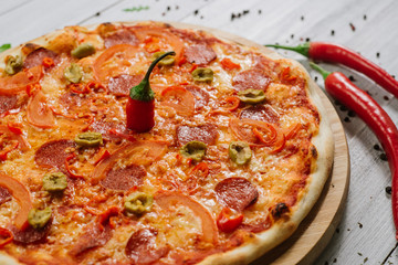 Pizza Pepperoni with mozzarella, salami, pepper and olives on the white wooden background