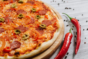 Pizza Pepperoni with mozzarella, salami, pepper and olives on the white wooden background