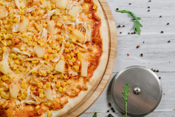 Pizza Americana with mozzarella, chicken fillet, pineapple and corn on the wooden background