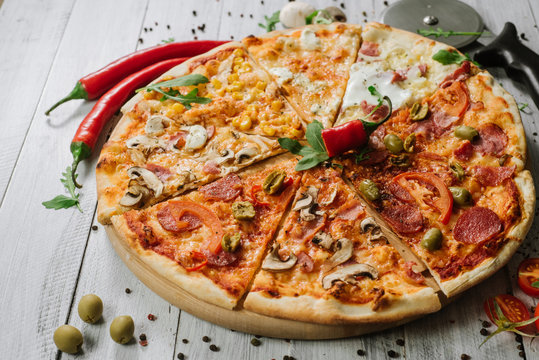 A slices on different kinds of pizza set in one rounded piece on wooden background