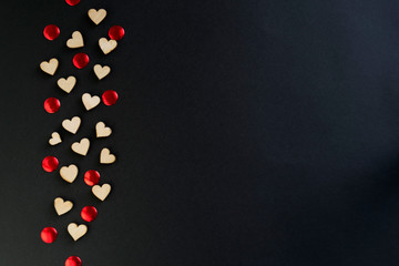 Valentine's Day background with hearts, borders of large and small felt hearts on a black table, flat lay