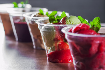 various ice cream desserts a plastic cups with mint leaf on wooden table