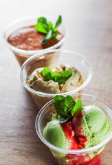 various ice cream desserts a plastic cups with mint leaf on wooden table