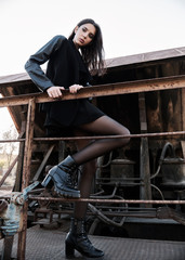 Fashion shot: portrait of cute rock girl (informal model) dressed in black jacket and skirt standing on train car