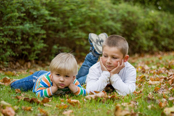 Naklejka na ściany i meble Cute little brother childrens lying on green grass in park
