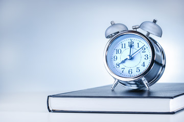 business, office, school and education concept. alarm clock on book.
