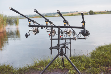Carp fishing rods standing on special tripods. Expensive coils and a radio system of crochet