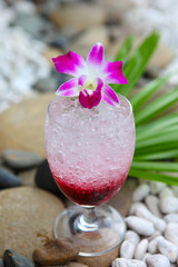 Glass of red cherry soda drink on stones background