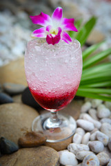 Glass of red cherry soda drink on stones background