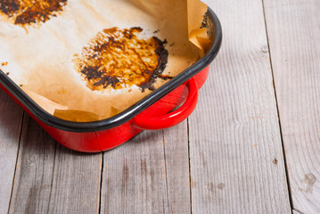 burned food prints on baking paper, old enamel frying pan on wooden table