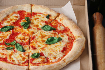 pizza in box cardboard. ingredients for pizza on dark stone background