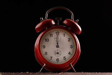 Red retro alarm clock on a dark background.