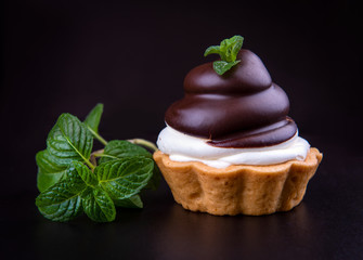 Small chocolate tarts (tartlets) with whipped mascarpone cheese on dark background