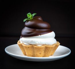 Small chocolate tarts (tartlets) with whipped mascarpone cheese on dark background