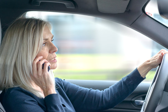 Mature woman chatting on her mobile in the car - Powered by Adobe