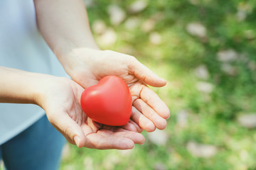 Close up of a red heart on a woman hand. It shows a love that is full of happiness. Combination of...