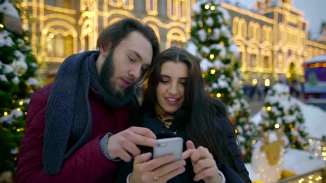 Young happy couple with smartphone in the city. Share memories and photos on social networks with an online mobile app. View files on your mobile device
