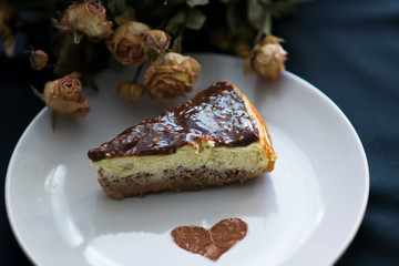 Cheesecake with chocolate and flowers on black background