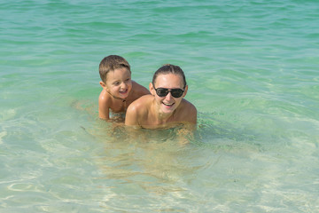 Fototapeta premium Happy smiling mother and her son playing and running on the beach. Concept of friendly family - Image