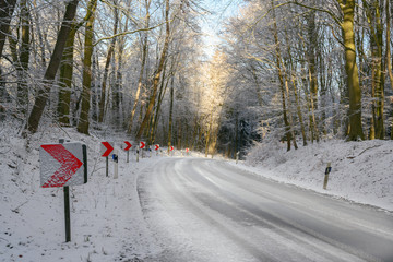 traffic signs with red arrows on a dangerous curve on an snowy country road through the winter...