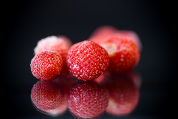 fresh frozen red ripe strawberries on a black