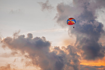 Parasailing in evening. Bright parachute on a background of a sunset