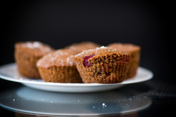 fresh sweet muffins with berries inside on black