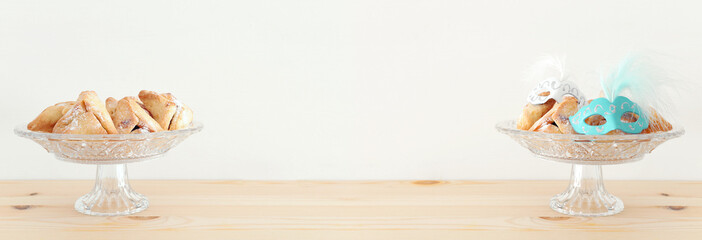 Purim celebration concept (jewish carnival holiday) over wooden table and white background.