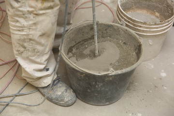 The construction worker mixes tile adhesive together with the water in the correct proportions.