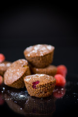 fresh sweet muffins with berries inside on black