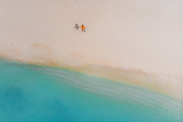 Fototapeta na wymiar Beautiful beach with white sand palm trees and clear blue sea. Couple on the beach