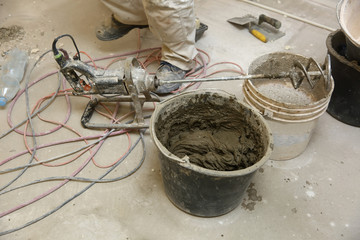 The construction worker mixes tile adhesive together with the water in the correct proportions.